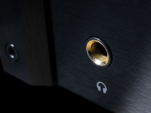 Close-up of a black audio jack with gold connector on a dark background